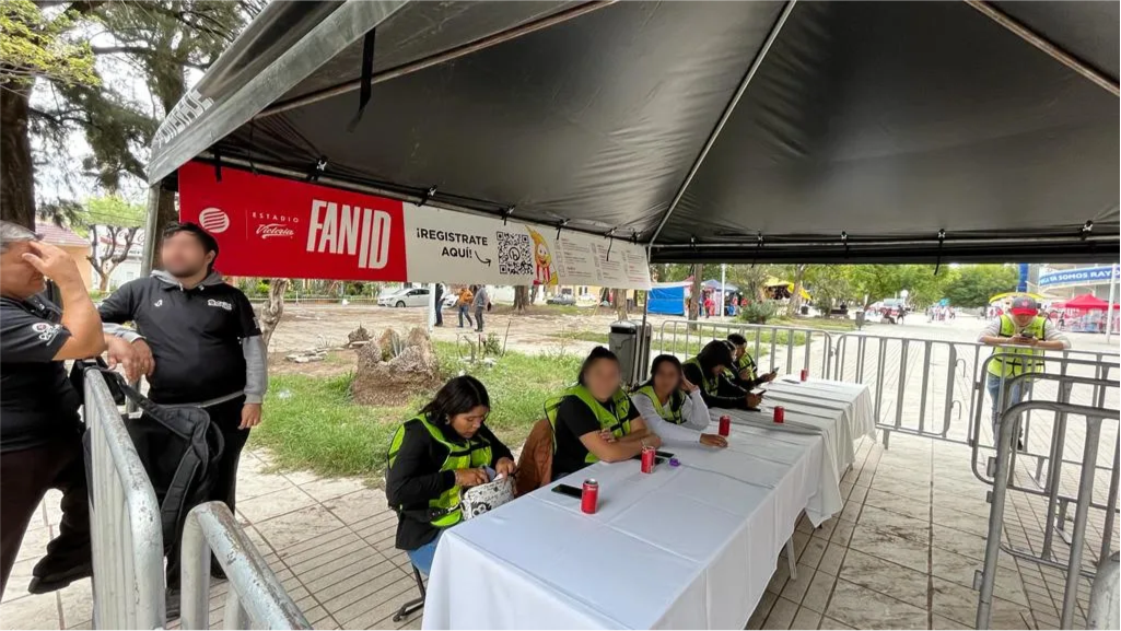 Carpa de registro de Fan ID en exteriores con personal sentado detrás de mesas.