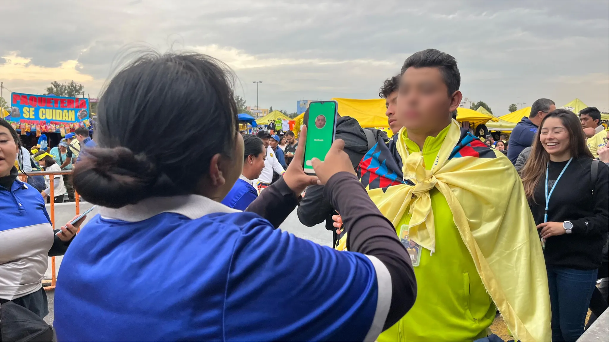 Personal del evento escaneando o revisando a un asistente que sostiene un documento verde.
